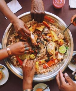 Travelers sharing a communal meal with locals, experiencing Teranga hospitality.